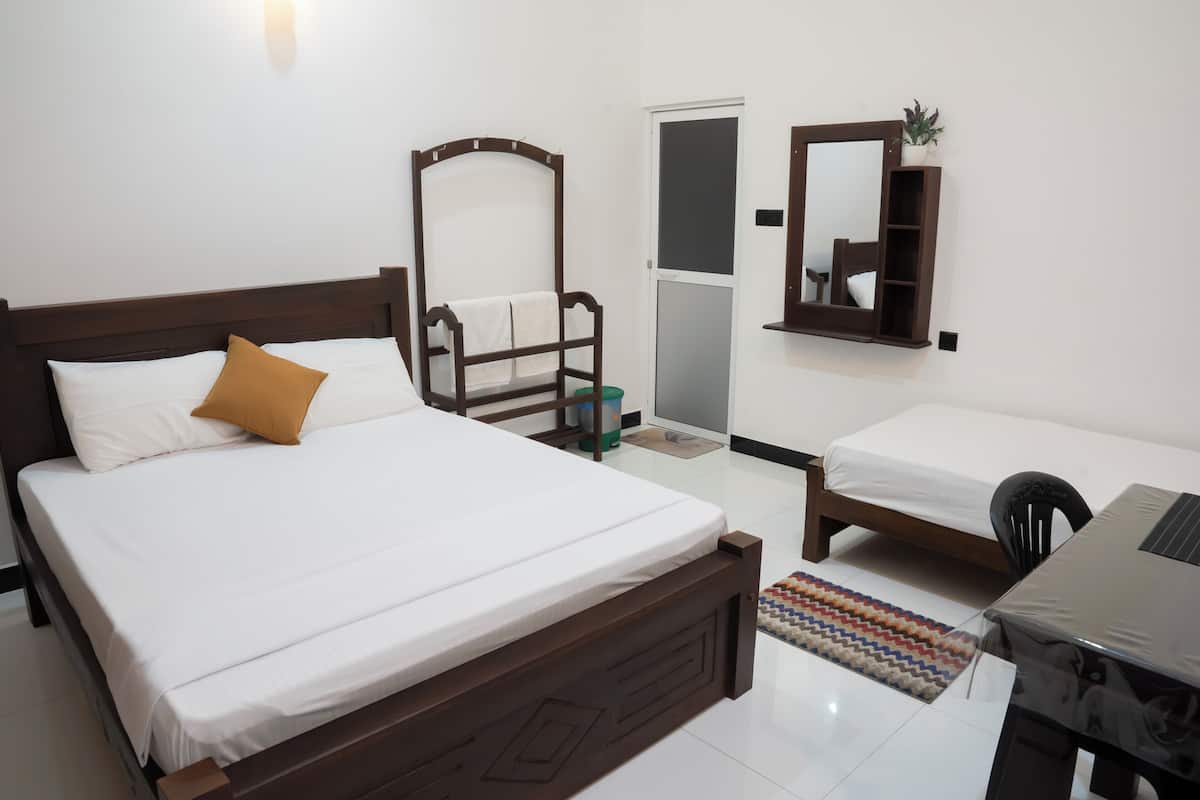 Une chambre à coucher avec un lit, une chaise, un bureau, un miroir et une porte.