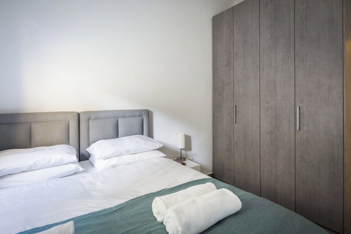 Une chambre d’hôtel comprenant un lit, des oreillers, une table de chevet, une lampe et une armoire.