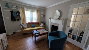 Ein Wohnzimmer mit einer Couch, einem Couchtisch, einem Kamin und einer Glastür.