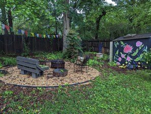 A garden with a wooden bench, a compost bin, and a small table with a green object on it. - Comfortable 3-bed/2bth house in Decatur, near Emory (Decatur)