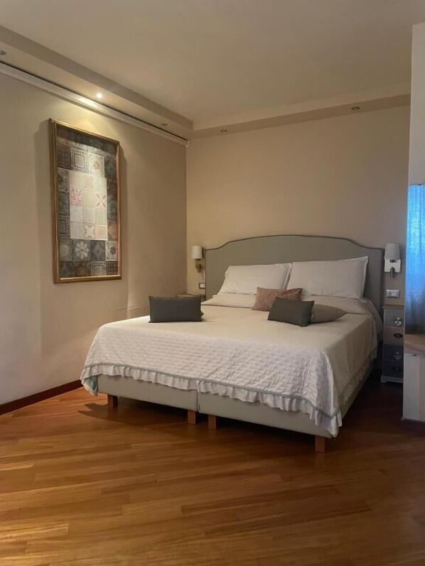 A bedroom with a bed, bedside tables, a wall-mounted light, and a framed artwork. - Locanda de Banchieri (Fosdinovo)