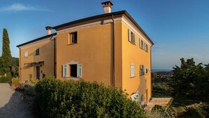 A two-story building with a flat roof, a chimney, and a large window on the second floor. - Locanda de Banchieri (Fosdinovo)