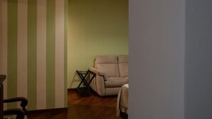 A room with a striped wall, a beige armchair, and a wooden floor. - Locanda de Banchieri (Fosdinovo)
