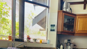 Keittiössä on puukuvioiset kaapit, Bosch-merkkinen astianpesukone, kahvinkeitin ja ikkuna, jossa on sälekaihtimet.