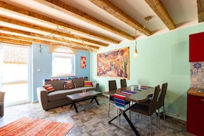 Une pièce comprenant une table à manger, des chaises, un canapé et une fenêtre.