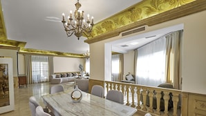 Een ruime eethoek met een marmeren tafel, elegante stoelen en een kroonluchter.