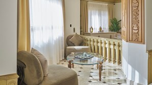 Een woonkamer met een bank, een glazen salontafel, een spiegel en een vloer met patroon.