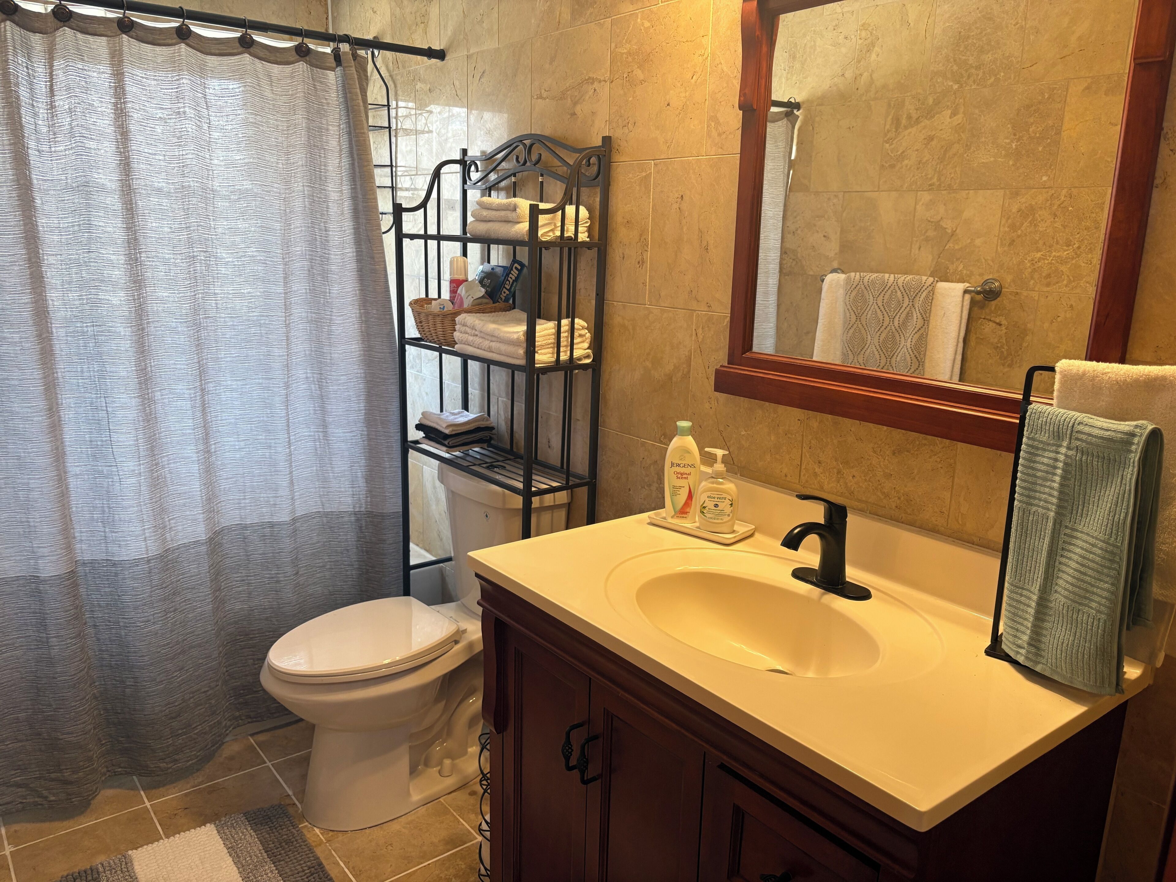 A bathroom with a toilet, sink, mirror, and towel rack.