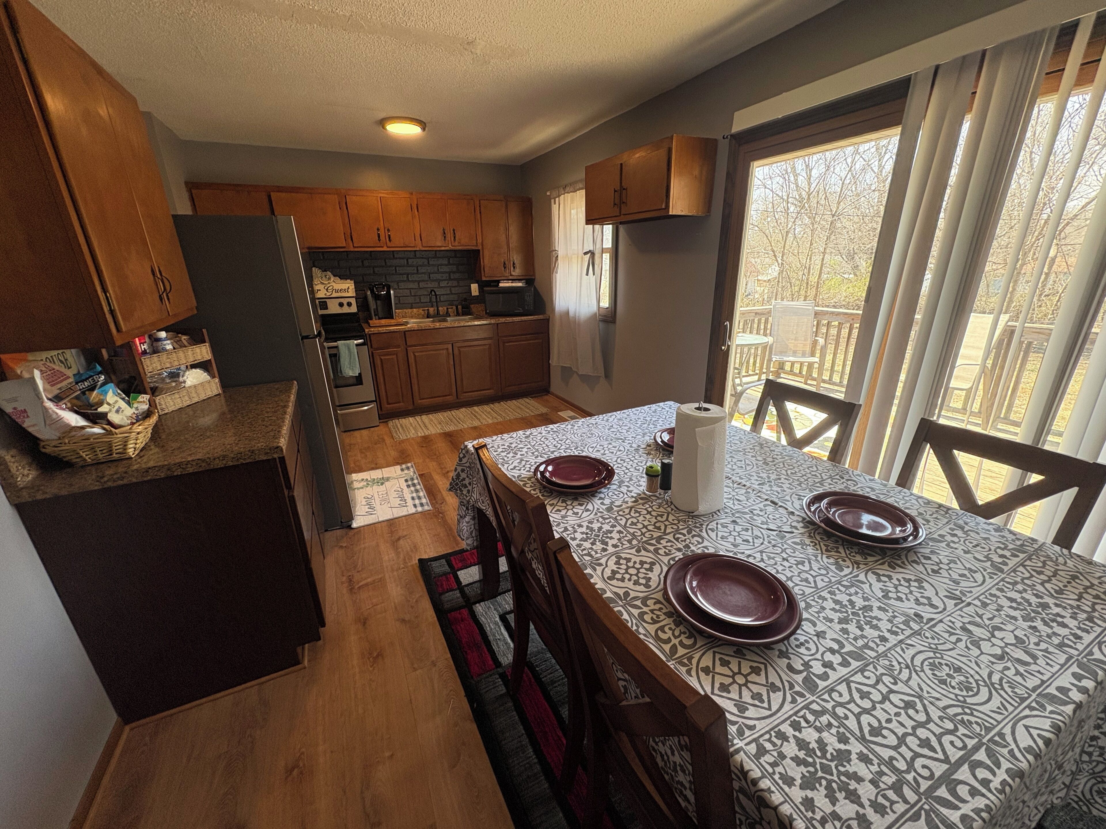 A kitchen with wooden cabinets, a dining table with plates, and a view through a window.
