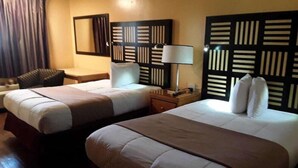 Une chambre d’hôtel avec deux lits, un bureau, une chaise et une lampe.
