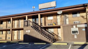 Un motel avec un panneau indicateur, un escalier et un parking.