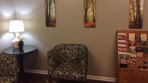 Une pièce avec une table ronde, une chaise et trois tableaux encadrés accrochés au mur.