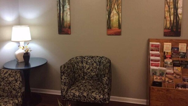 Une pièce avec une table ronde, une chaise et trois tableaux encadrés accrochés au mur.