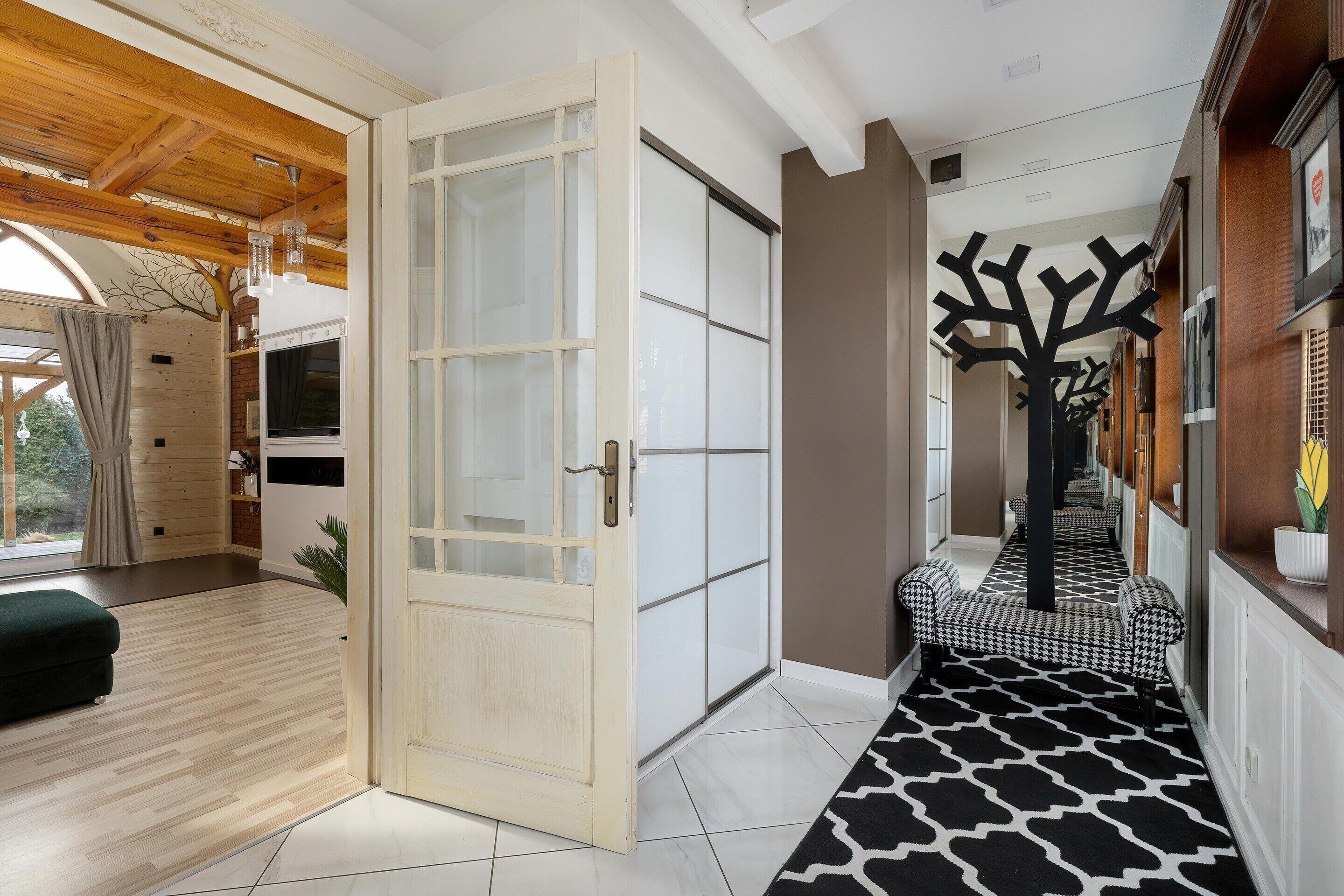 A hallway with a patterned carpet, a wooden door, and a black tree-shaped decoration.