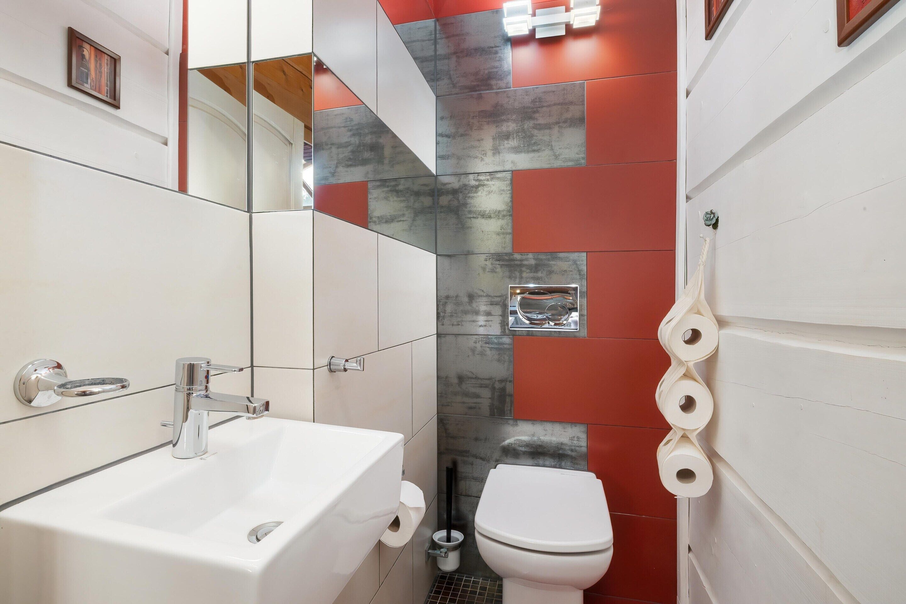 A bathroom with a white sink, chrome faucet, and a toilet.