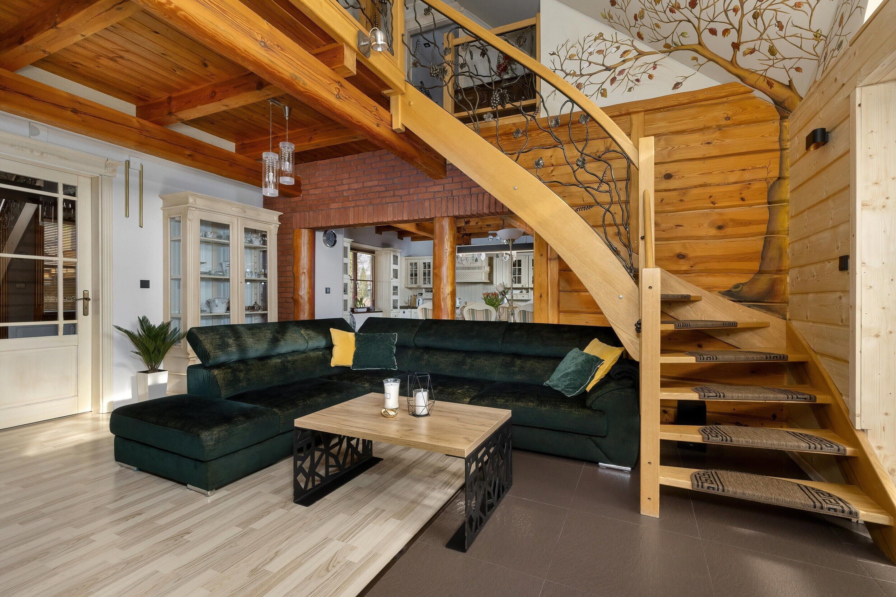 A modern living room with a wooden staircase, a sectional sofa, and a coffee table.