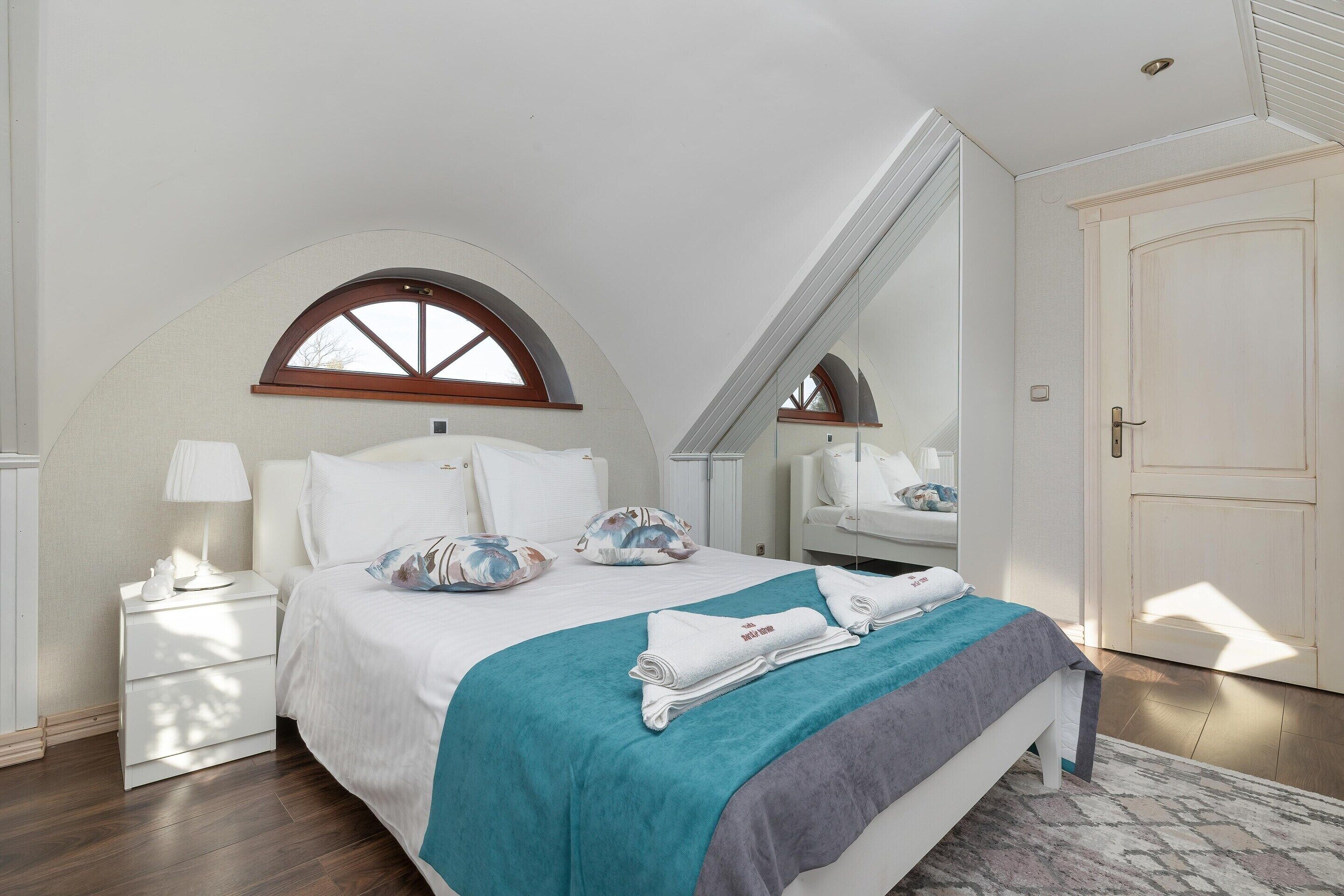 A bedroom with a bed, a nightstand, a dresser, a mirror, and a door.
