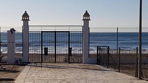 A paved pathway leading to a gated entrance with a view of the ocean. - Apartment in Natura World With Pool (Vera)