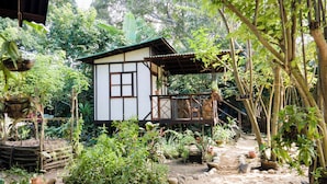 Ein traditionelles Haus mit Balkon, umgeben von üppiger Vegetation.