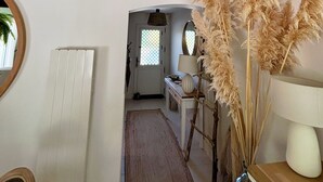 A hallway with a white radiator, a wooden door, a mirror, and a shelf with dried plants. - Villa 5 minutes from the sea! Near Royan (Semussac)