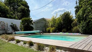 A wooden deck leading to a swimming pool with a house in the background. - Villa 5 minutes from the sea! Near Royan (Semussac)