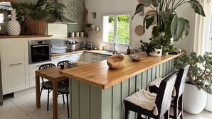 A kitchen with a central island, wooden chairs, and potted plants. - Villa 5 minutes from the sea! Near Royan (Semussac)
