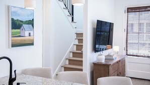 A modern interior with a dining area, staircase, and a television on the wall. - The Tanglewood, 3BR by Velvet Ditch Villas (Oxford)