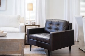 A modern living room with a dark leather armchair, a white sofa, a wooden coffee table, and a floor lamp. - The Tanglewood, 3BR by Velvet Ditch Villas (Oxford)