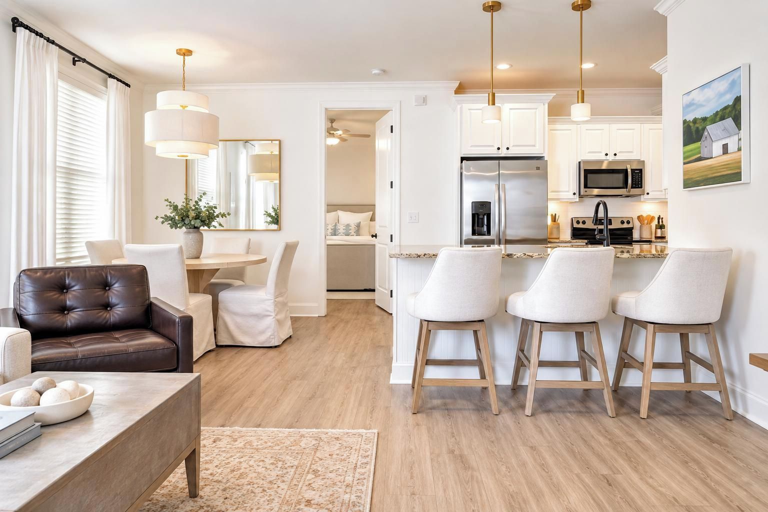 A modern kitchen with white cabinets, stainless steel appliances, and a bar area with stools.