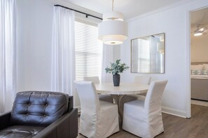 A modern dining area with a round table, white chairs, a black leather chair, a potted plant, and a large mirror on the wall. - The Tanglewood, 3BR by Velvet Ditch Villas (Oxford)