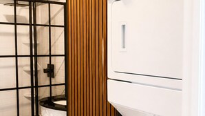 A laundry room with stacked washers and dryers, a black metal rack, and a white marble floor. - 10 minutes from the beach-Apartment in charming Shallotte with AC (Shallotte)