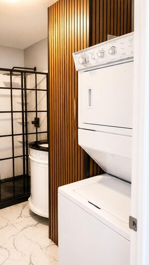Una sala de bugaderia amb piles de rentadores i assecadores, un suport metàl·lic negre i un sòl de marbre blanc.