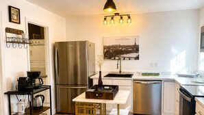 A modern kitchen with a stainless steel refrigerator, a coffee station, a dining table with chairs, and a sink. - 10 minutes from the beach-Apartment in charming Shallotte with AC (Shallotte)