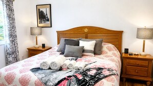 A neatly made bed with rolled towels, a framed picture on the wall, and a wooden headboard. - 10 minutes from the beach-Apartment in charming Shallotte with AC (Shallotte)
