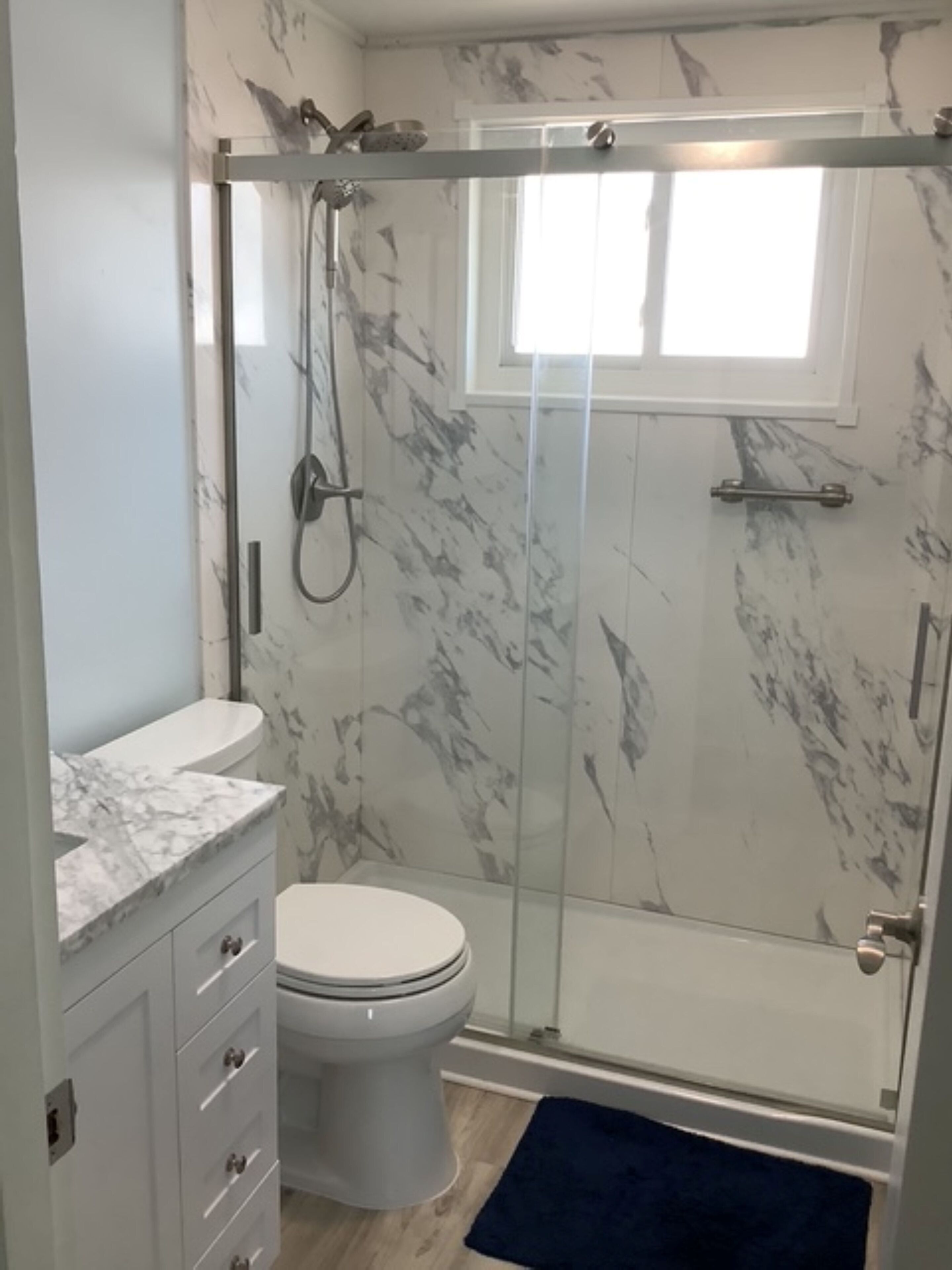 A bathroom with a shower, toilet, and vanity.