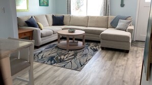 A living room with a beige sofa, a round coffee table, and a patterned rug.