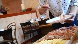 Una persona sirve comida de un plato con diferentes carnes y quesos.