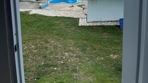Vista desde una puerta a un patio trasero con piscina, una estructura de techo de paja y vista al océano.