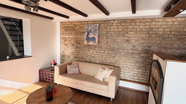 Ein Wohnzimmer mit einer Couch, einem Couchtisch, einem Kamin und einer Ziegelwand.