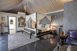 A four-poster canopy bed with a nightstand, a sitting area with a bench, and a large rug on the floor. - Eden Lodges & Spa-boutique Hotel de Luxe (Marrakech)