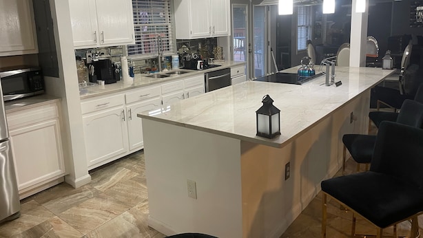 A modern kitchen with white cabinetry, a central island, and pendant lighting.