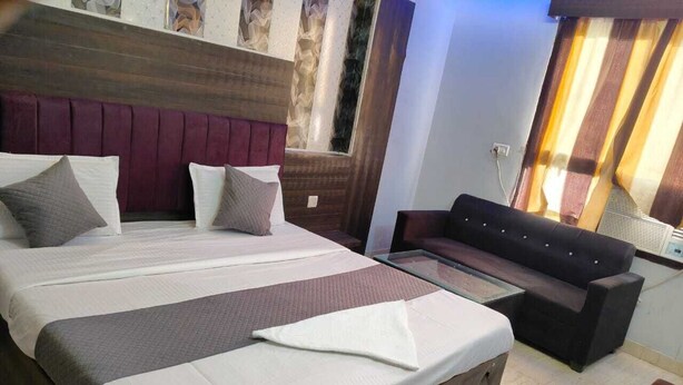 A hotel room with a large bed, a sofa, and a small table. - Hotel Park Avenue  (Lucknow)