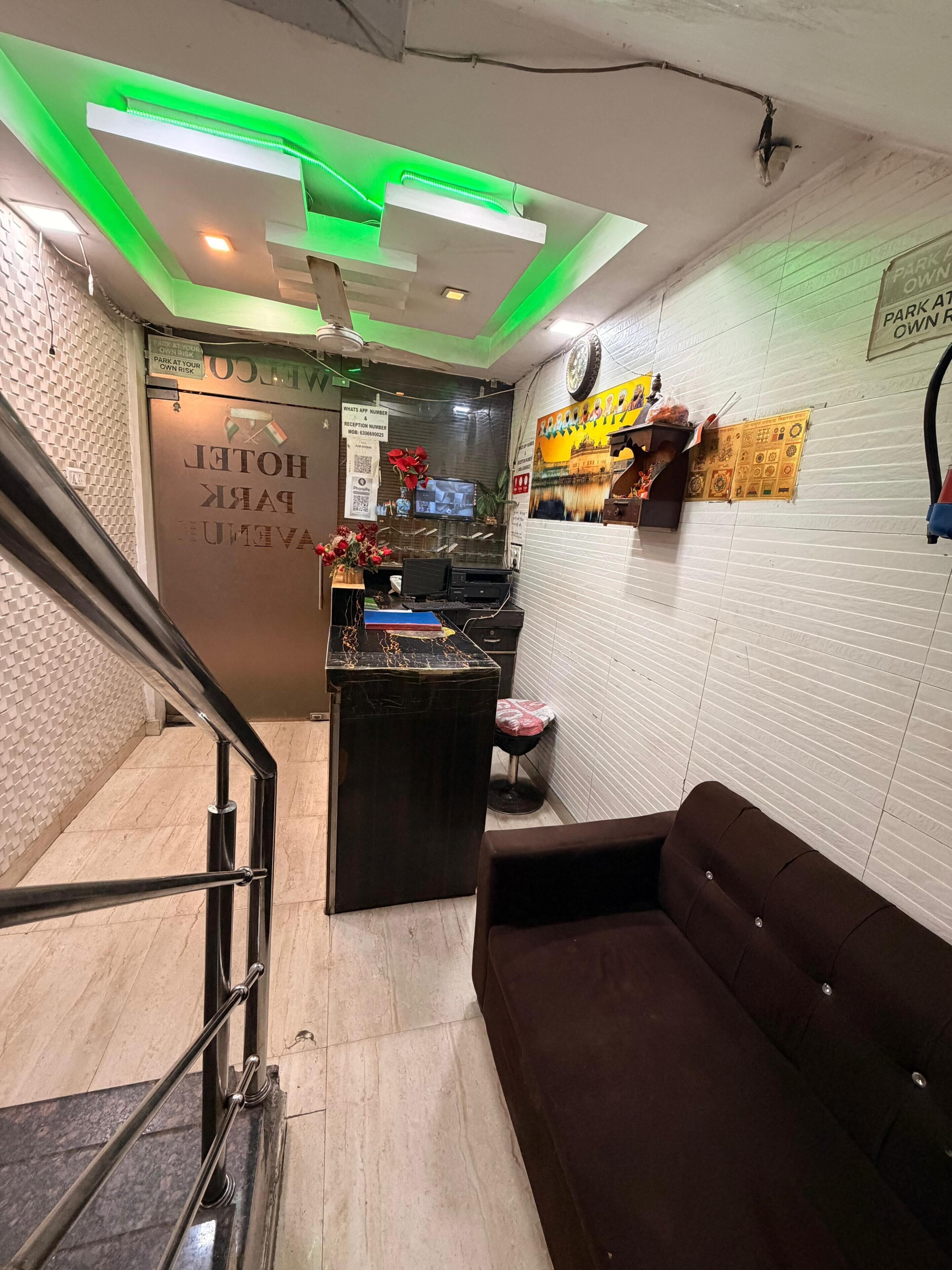 Eine Hotelhalle mit einer Rezeption, einer Couch, einer Treppe und einer Wand mit einem Schild.