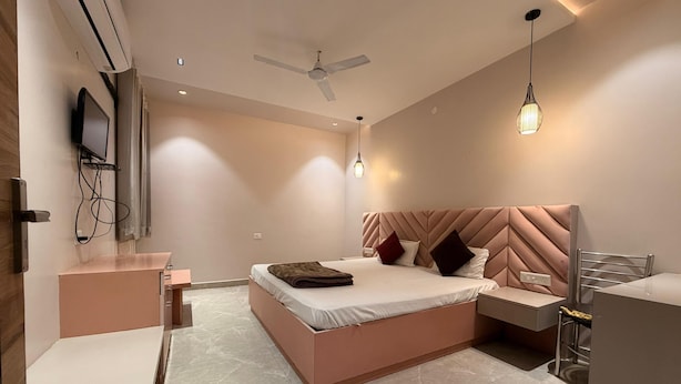 A modern bedroom with a bed, bedside tables, a TV, and a ceiling fan. - Hotel Park Avenue (Lucknow)