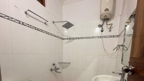 A small bathroom with a toilet, a red bucket, a showerhead, and a sink. - Hotel Park Avenue (Lucknow)