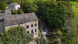 Un edificio con fachada de piedra, una escalera visible y un río cercano.