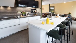 Una cocina moderna con una isla central, taburetes de bar y un comedor con sillas.
