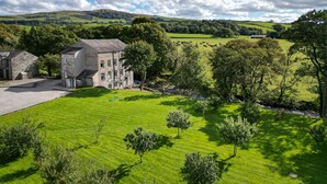 A rural landscape with a stone building, green fields, and a river. - Upper Riverside Mill - Luxury Cottages (Kendal)