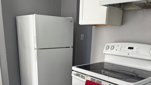 Uma cozinha com geladeira branca, forno branco e uma toalha vermelha pendurada na maçaneta do forno.