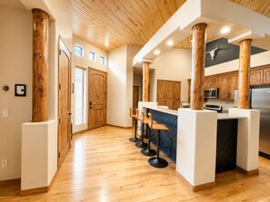 A modern kitchen with wooden beams, a bar area, and a large refrigerator. - Escape the Arizona Heat + 2 King Suites + Bunk Room (Show Low)
